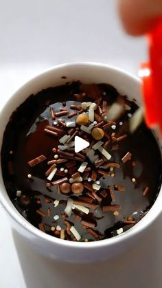 a cup filled with chocolate and sprinkles on top of a white table