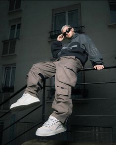 a man sitting on top of a stair rail next to a building with his feet up