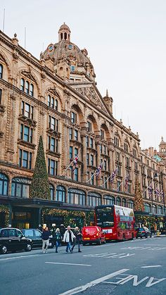 people are walking down the street in front of some very tall buildings with christmas decorations on them