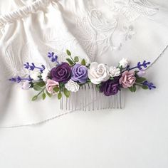 purple and white flowers are on top of a comb that is attached to the side of a dress