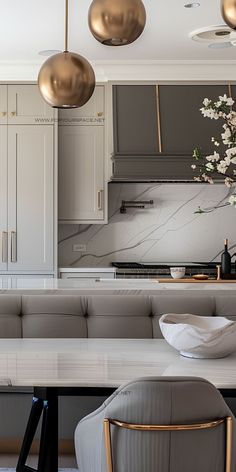 a modern kitchen with marble counter tops and gold pendant lights hanging from the ceiling above