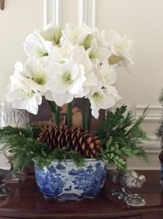 a vase with white flowers and pine cones