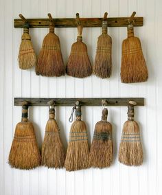 several brooms hanging on a wooden rack