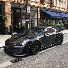 a black sports car parked on the side of the road in front of a building