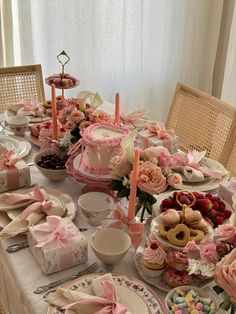 a table is set with pink and white dishes, plates, cups, and napkins