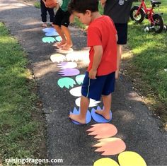 two young boys playing with paper plates on the ground in front of some trees and grass