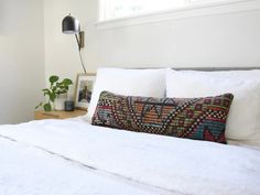 a bed with white sheets and pillows in a bedroom