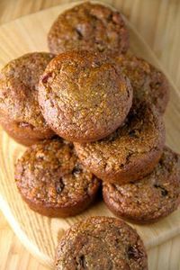 a pile of muffins sitting on top of a wooden cutting board