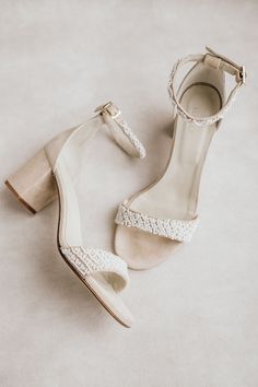 a pair of white high heeled shoes sitting on top of a floor