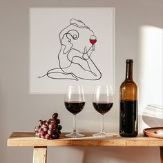 two glasses of wine sit on a table next to a bottle of wine and some grapes