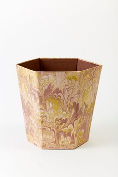 a brown and yellow vase sitting on top of a white table