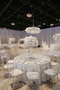 a banquet hall with tables and chairs set up for a formal function, decorated in white flowers