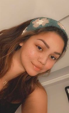 a woman with freckles and a headband on posing in front of a mirror