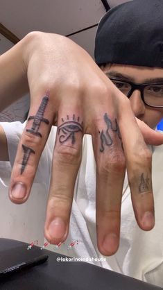 a man with two fingers that have tattoos on them, and one has an eye in the middle