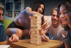 three people playing with wooden blocks on a table