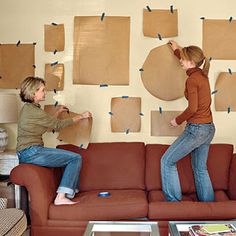 two women standing on the back of a couch with pieces of cardboard taped to it