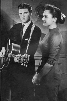 a man holding a guitar next to a woman