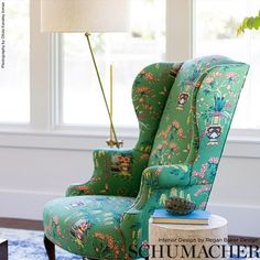 a green chair sitting in front of a window next to a book on top of a table