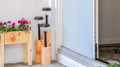 two wooden planters with flowers in them on the side of a building next to an open door