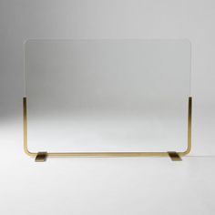 a glass and brass frame on a white surface with the reflection of an object in it