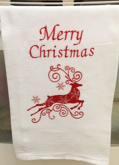 a white towel hanging from a clothes line with merry christmas written on it and a red reindeer