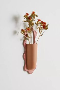 a vase with flowers in it hanging on the wall next to a hook that is shaped like a planter