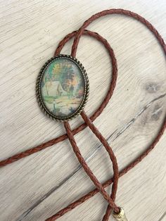 a brown cord with a small pendant on it's end sitting on top of a wooden table