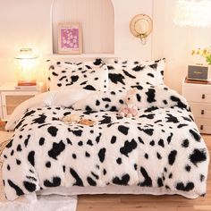 a bed with black and white animal print comforter on it in a bedroom next to a dresser