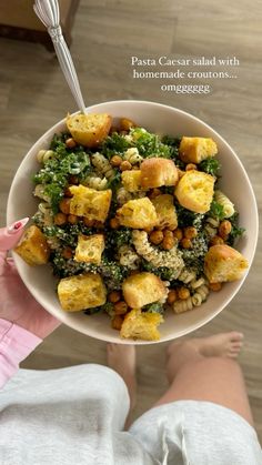 a person holding a bowl full of food with broccoli and tofu in it