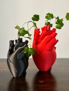 two heart shaped vases sitting on top of a wooden table next to each other