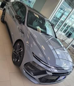 a silver sports car is parked in a showroom with its hood up and windows open