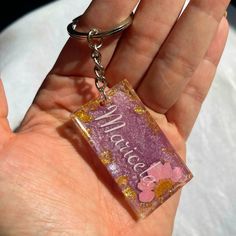 a hand holding a pink and gold keychain with the word welcome on it