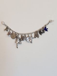 "JB Sterling bracelet with 18 charms! Each charm is marked Sterling silver and two move. The poodle has a crown and when you press it's red tongue, the eyes close and there is a bell Charm where the dinger moves. The other charms are: * surfer board * state of Hawaii * Bridesmaid * bell with moving dinger * Oregon banner * Dinosaur * Blue enamel bird * Virginia city Nevada * gold miner * octopus * state of Georgia * pineapple * totem pole * Happy birthday * Canada * Louisiana The bracelet measur Adjustable Metal Charm Bracelet With Removable Charms, Adjustable Silver Bracelet With Logo Charm, Silver Bracelets With Logo Charm For Gift, Silver Bracelets With Logo Charm As Gift, Silver Charm Bracelet With Logo For Gift, Silver Charm Bracelet With Logo As Gift, Nickel Free Metal Name Bracelet In Silver, Nickel Free Silver Metal Name Bracelet, Nickel-free Silver Metal Name Bracelet