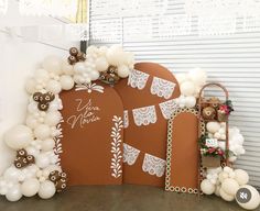 an arch decorated with white balloons and brown paper decorations for a wedding or bridal party