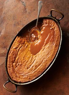 a cake in a pan with caramel sauce on top and a spoon sticking out of it