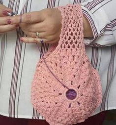 a woman holding a pink crocheted purse