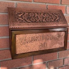 a plaque on the side of a brick wall reads valerie court 40, with flowers and leaves