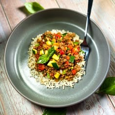 a plate with rice, meat and vegetables on it next to a green leafy plant