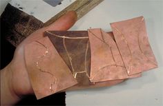 a hand holding four pieces of copper foil