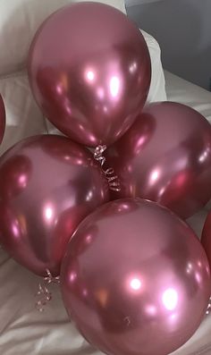 a bunch of pink balloons sitting on top of a bed