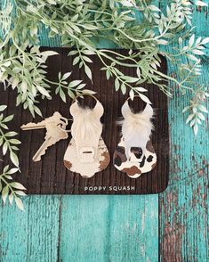 two pieces of paper cut out of animal heads on a wooden surface with green leaves