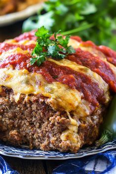 a meatloaf covered in sauce and cheese on a blue plate with parsley