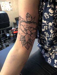 a woman's arm with a tattoo on it and flowers around the arm area