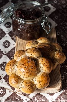 hot cross buns on a cutting board next to a jar of raisin jam