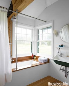 a bathroom with a sink, mirror and bathtub next to a window in the wall