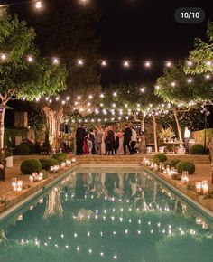 an outdoor pool with candles and lights around it