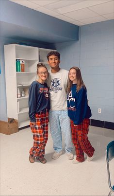 three young people standing next to each other in front of a book shelf and bookshelf