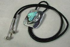 "Sterling silver and turquoise southwest bolo tie. The rectangle is 2\" tall x 1 9/16\" wide. The pretty turquoise stone is 1 3/16\" tall. The cord and tips measure 36\". A nicely done hand made leaf decorates the side of the stone. Stamped EJ on the back. There are some surface scratched on the silver from being worn. We polished the silver. Good condition." Turquoise Bolo Tie, Bolo Ties, Blue Topaz Necklace, Topaz Necklace, Black Onyx Ring, Bolo Tie, Topaz Stone, Domed Ring, Onyx Ring