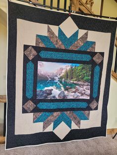 a blue and black quilt hanging from a stair case next to a handmade wall hanging