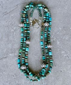 This good-looking Necklace showcases 3 strands of Mixed Turquoise, including 6-by-9mm Drum Beads, 4-by-6mm Rondelles, 6mm Triangles and 4mm Heishi. The Turquoise displays a variety of blue and green hues, creating a color palate that is visually engaging. It is paired with several other complementary elements, notable of which are the 11-by-12mm Hill Tribe Silver Ridged Bicones. The Bicones are beautifully crafted and polished to a soft luster. Other elements are comprised of: 6mm green Rutilate Southwest Design, Hill Tribe Silver, Color Palate, Green Hues, Color Depth, Rutilated Quartz, Toggle Clasp, Strand Necklace, Triangles